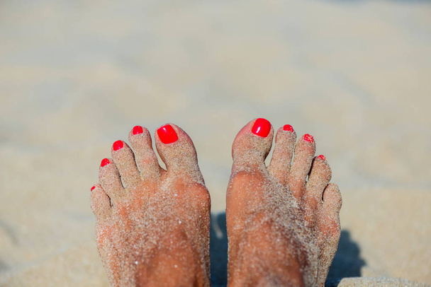 Koncept letní dovolené samice bosá s červeným lakem na pískovém pozadí - selektivní zaostření, kopírovací prostor - Fotografie, Obrázek