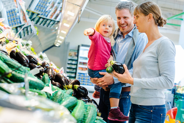 Οικογένεια με παιδάκι που διασκεδάζουν αγοράζοντας προϊόντα σε σούπερ μάρκετ - Φωτογραφία, εικόνα