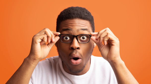 Здивований американець-афроамериканець, який торкається своїх окулярів. - Фото, зображення