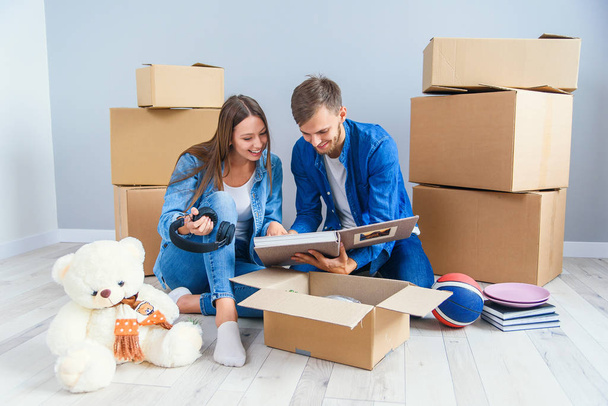 Young couple unpacking things after moving into new house - Фото, изображение