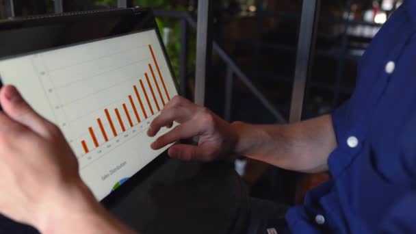 Businessman makes a presentation using a convertible laptop with touchscreen in tent mode. Freelancer works with 2 in 1 transformer notebook with touch display. Finger pointing at graphic chart. - Footage, Video