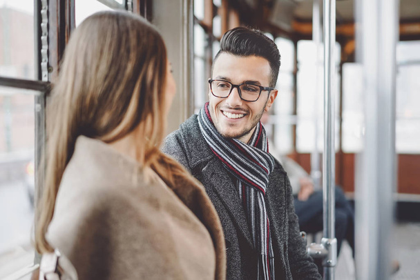 Happy couple having conversation while going to work in bus - Young people traveling in vintage tram transportation - Love relationship and travel lifestyle concept - Photo, Image