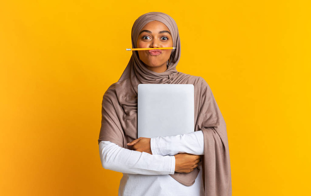 Divertido afro musulmán chica estudiante en hijab sosteniendo lápiz como bigote
 - Foto, imagen