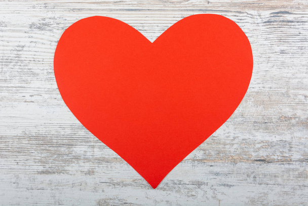 Velké papírové červené srdce pro nápis leží na bílém dřevěném pozadí. Valentýn, svatba, projev lásky. Prostor pro text, pohled shora, plochá poloha, kopírovací prostor. - Fotografie, Obrázek