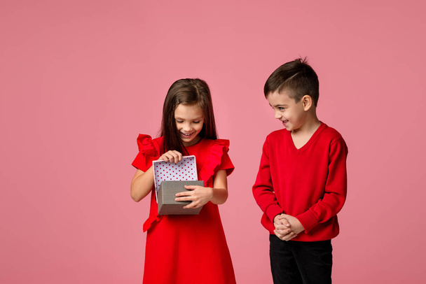 Happy little child boy gives smiling girl a gift box - Zdjęcie, obraz