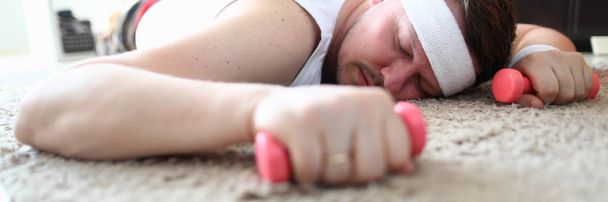 Vyčerpaný muž ležel na podlaze s Dumbrolli v ruce - Fotografie, Obrázek