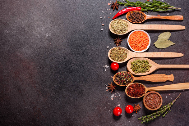 Um conjunto de especiarias e ervas. Cozinha indiana. Pimenta, sal, páprica, manjericão e outros em um fundo escuro
 - Foto, Imagem