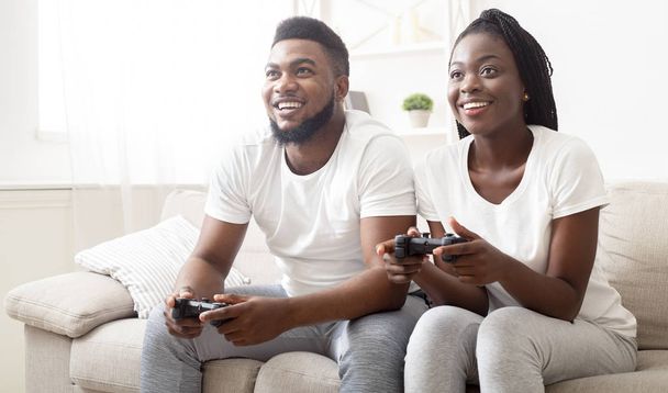Веселая афроамериканская пара, играющая в видеоигры дома вместе
 - Фото, изображение