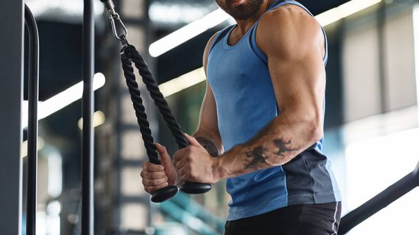 ジムでトレーニング機器を使って運動する筋肉の男 - 写真・画像