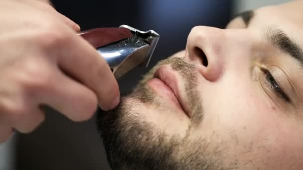 Barber clipping clients mustache with machine in barbershop - 映像、動画