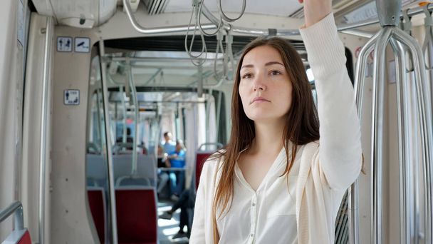 lady stands in tram holding handrail travelling to city - Photo, Image