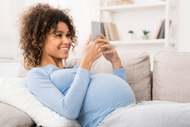 Mujer embarazada afroamericana navegando en el teléfono inteligente, espacio libre
 - Foto, imagen