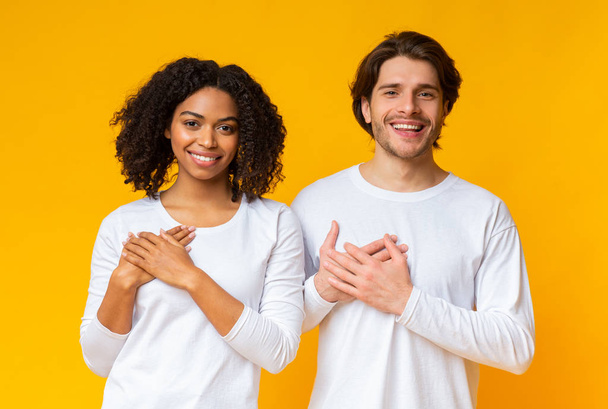 Remerciant couple multiracial exprimer sa gratitude avec les mains sur la poitrine
 - Photo, image