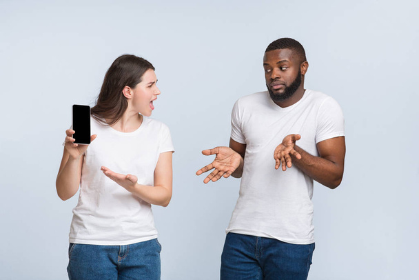 Angry girlfriend asking explanation from her unfaithful boyfriend, demonstrating his smartphone - Photo, Image
