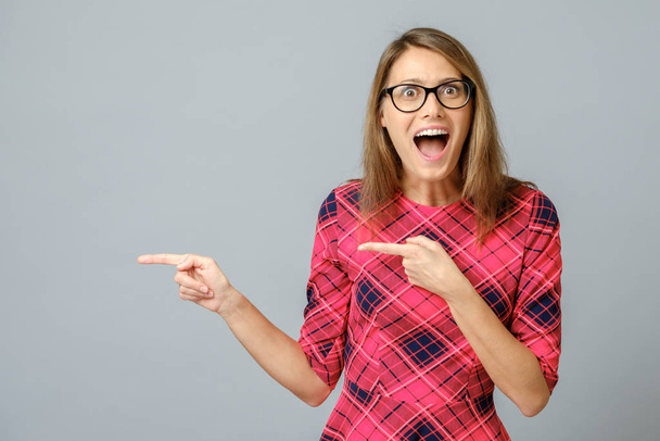 Portrait of amazed and excited brunette female pointing with forefinger - 写真・画像