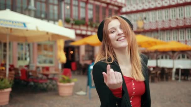 Red-haired girl walks down street turns, turns smiles looks at the camera - Materiał filmowy, wideo