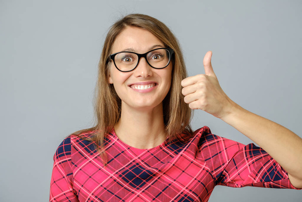 Happy caucasian female wearing red gress making thumb up sign - Φωτογραφία, εικόνα