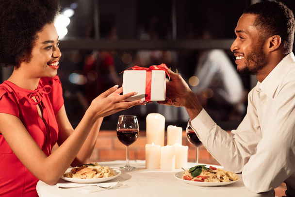 レストランでのデート中にガールフレンドにバレンタインプレゼントを与える男 - 写真・画像