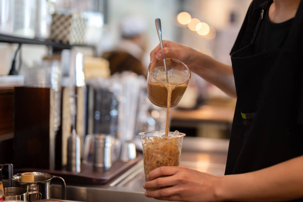 Бариста-бариста наливает кофе в стакан для еды на вынос в кафе
. - Фото, изображение