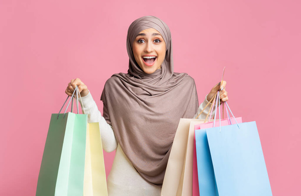 Muchacha musulmana emocionada sosteniendo gran cantidad de bolsas de compras y tarjeta de crédito
 - Foto, imagen