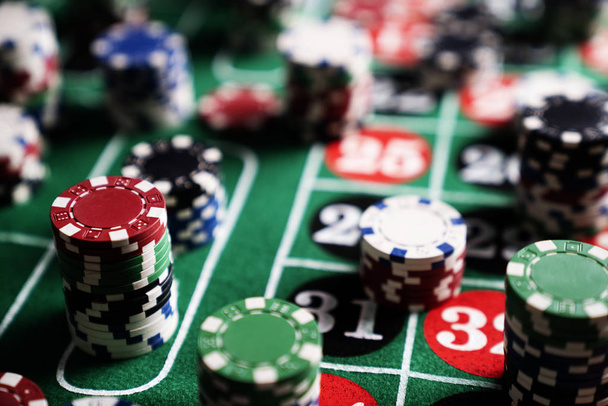Стопка фишек казино на зеленом столе для игры в покер
 - Фото, изображение