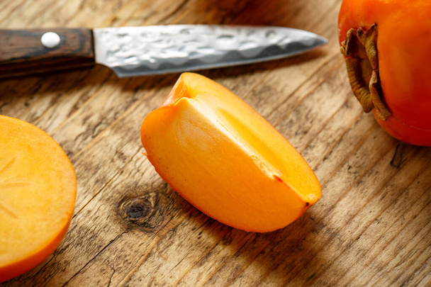 Raw ripe persimmons fruits slices on wooden board - Фото, зображення