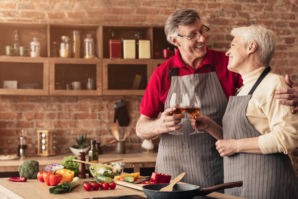 Boldog nyugdíjasok élvezik az esti pohár bort a konyhában - Fotó, kép