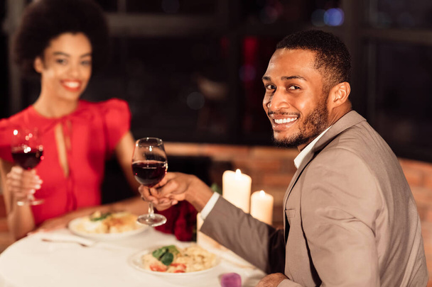 Veselý pár drží sklenice na víno s úsměvem slaví Valentýna v restauraci - Fotografie, Obrázek