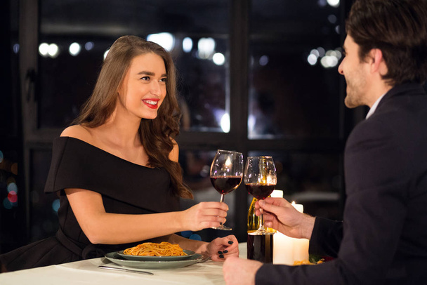 Happy couple in love clinking with wine Valentine date - 写真・画像