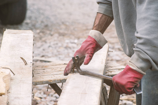 ξυλουργός με βρώμικα ρούχα εργασίας εργάζεται σε ένα εργοτάξιο - Φωτογραφία, εικόνα