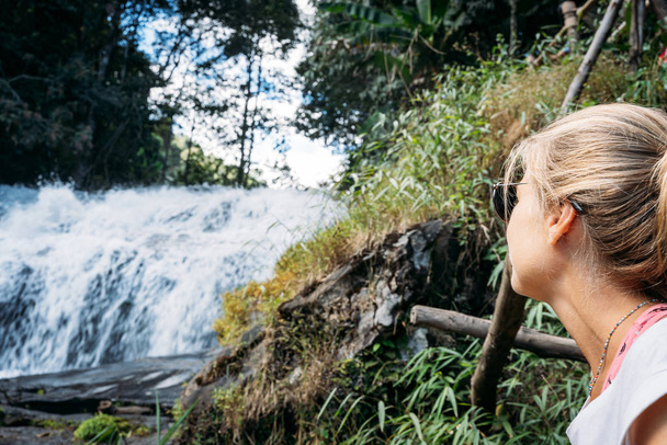 Блондинка смотрит на водопад в джунглях Таиланда - Фото, изображение