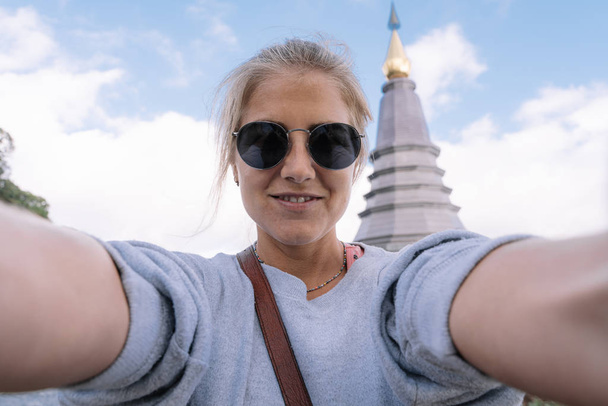 Fille blonde faire un selfie avec la pagode Chiang Mai en arrière-plan en Thaïlande - Photo, image