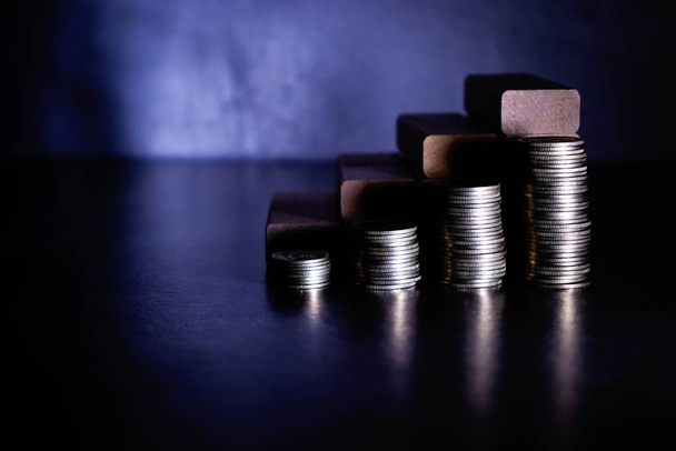 Piles of coins and wooden blocks in the form of steps on a dark background. Career ladder concept for successful business development, investment and profit growth. - Photo, Image