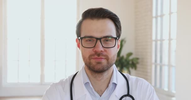 Smiling man doctor wear white uniform looking at camera, closeup - Imágenes, Vídeo