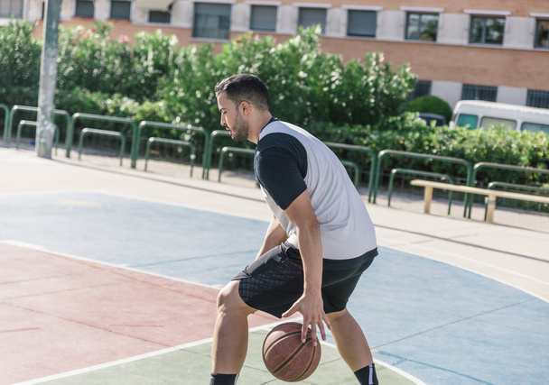 Un sportif fort joue au basket très concentré pour garder une trace de sa balle
 - Photo, image