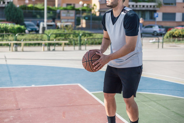 Athletic body sportsman prepares to throw a shot with his basket ball on a city court - Photo, Image