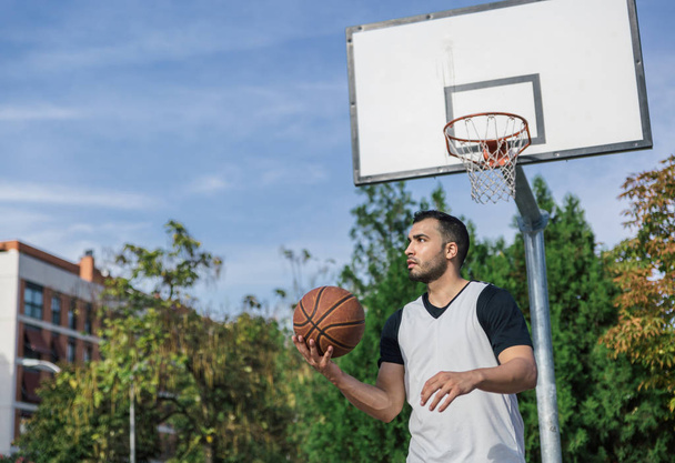 Young man plays basketball alone on an urban court with his back to the basket and the board - Foto, Imagem