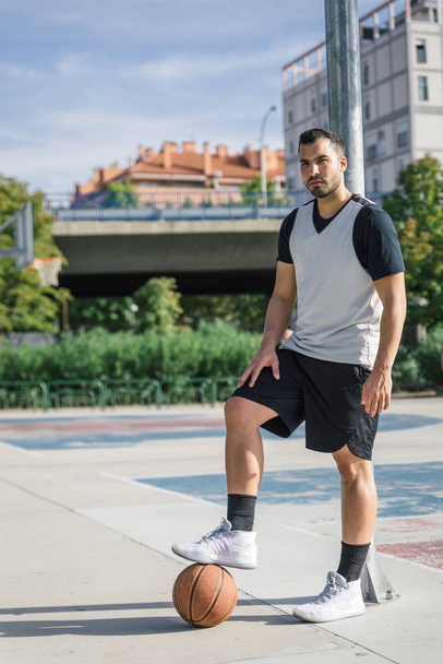 Atrakcyjne pozy sportowca wspierane jego koszykówki wspierane na kolumnie na torze miejskim - Zdjęcie, obraz