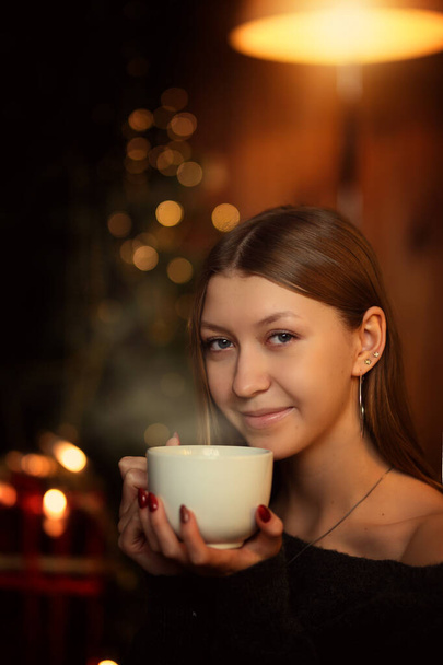 smiling young girl drinks hot drink - Fotó, kép