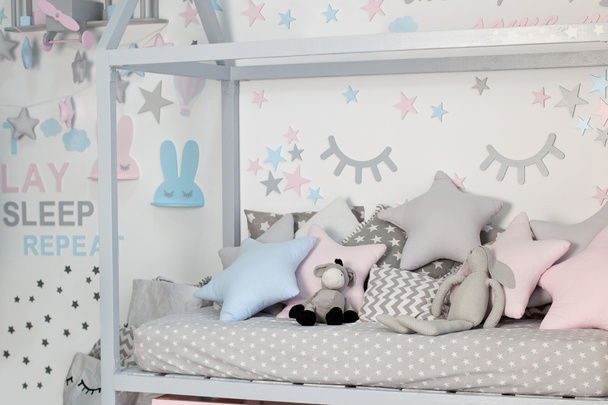 A gyerekszoba belseje játékokkal. Skandináv design gyermekszoba egy fa ágy formájában ház, designer bútorok, puha játékok és párnák. Házi dekoráció. Óvoda. játszószoba - Fotó, kép