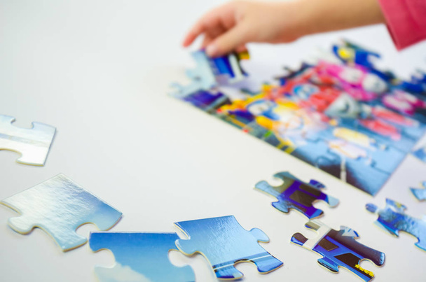 Close-up little girl collects puzzle at home at the table - Photo, Image
