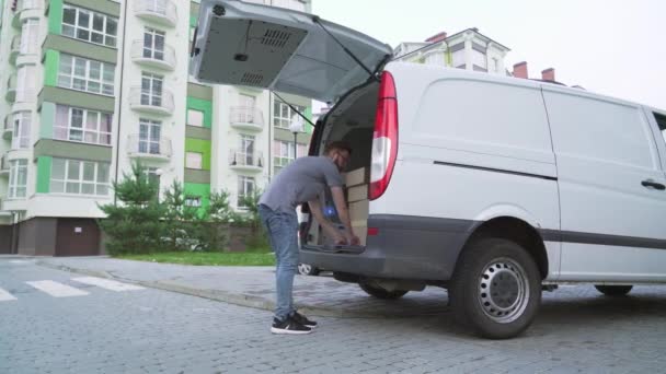 Brodatego kuriera rozładowującego kartony z bagażnika samochodowego - Materiał filmowy, wideo