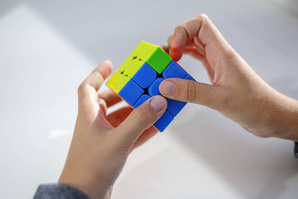 Perm, Russia, September 28 2019: Rubik's cube in the hands of a boy. The child holds a Rubik's cube on a light background, playing with it. Close up. - Foto, immagini