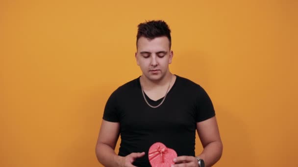 Surprised young man keeping pink box, biting nails. - Záběry, video