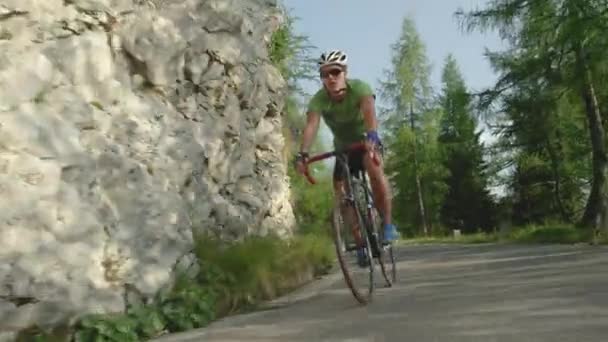 LOW ANGLE: Athletic man riding his road bicycle down the empty asphalt road. - Filmmaterial, Video