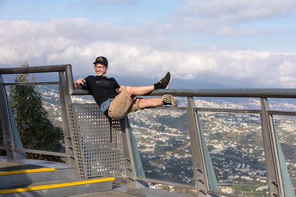 Cabo Girao, Madeira, Portugal - April 18, 2018: A man showing off his girlfriend on the railing of the Cabo Girao on Madeira Island, Portugal, the highest cliff in Europe - 写真・画像