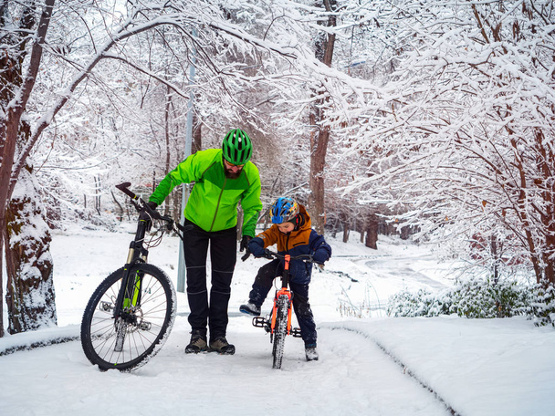 Vater und Sohn mit Fahrrädern im Winterpark - Foto, Bild