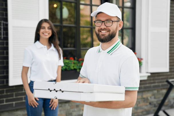Smiling deliveryboy holding boxes of pizza. - Zdjęcie, obraz