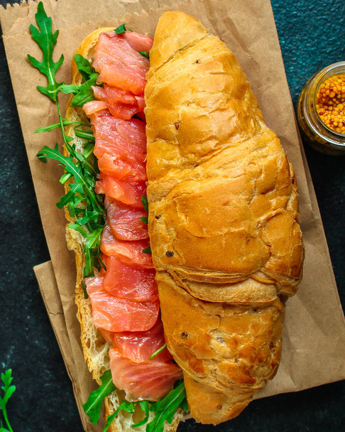 rybí sendvič se zeleninou, Smorrebrod (solený losos, croissant, chléb, rukola a další ingredience) menu. jídlo pozadí. pohled shora. kopírovat prostor - Fotografie, Obrázek