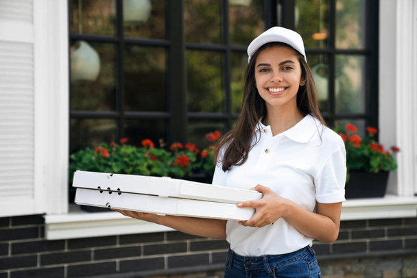 Smiling deliverywoman holding boxes of pizza. - Φωτογραφία, εικόνα